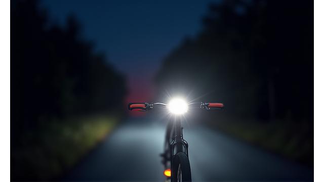 Cyclist riding at night, clearly visible due to bright lights and reflective gear.